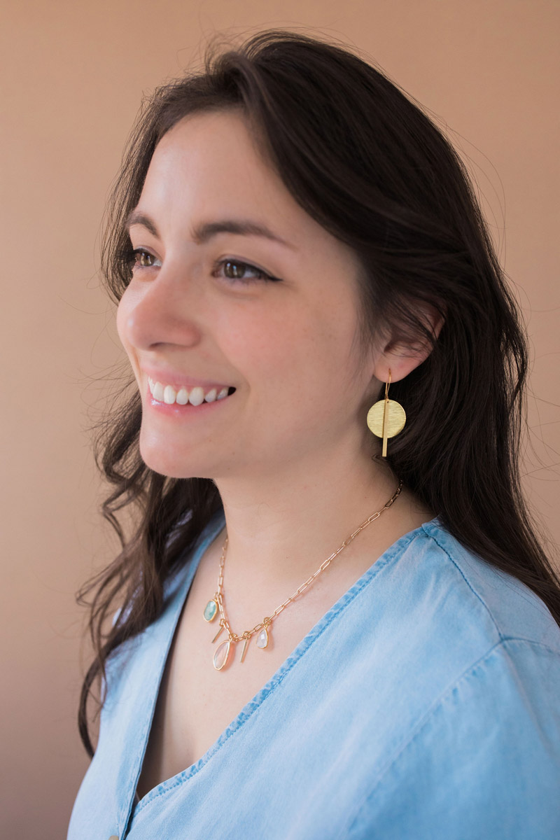 Smiling woman in a blue blouse modeling the Gaze of the Goddess earrings and the Hera Necklace.