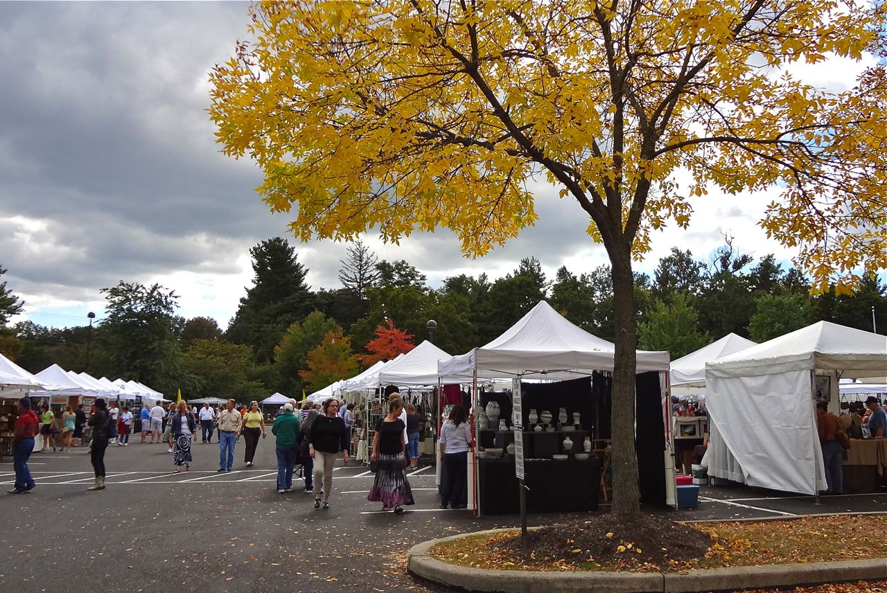 People attending an outdoor artisan market with white tents