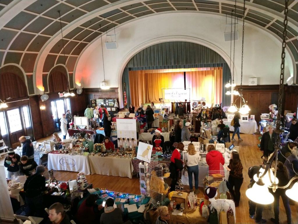 An indoor artisan market crowded with holiday shoppers.