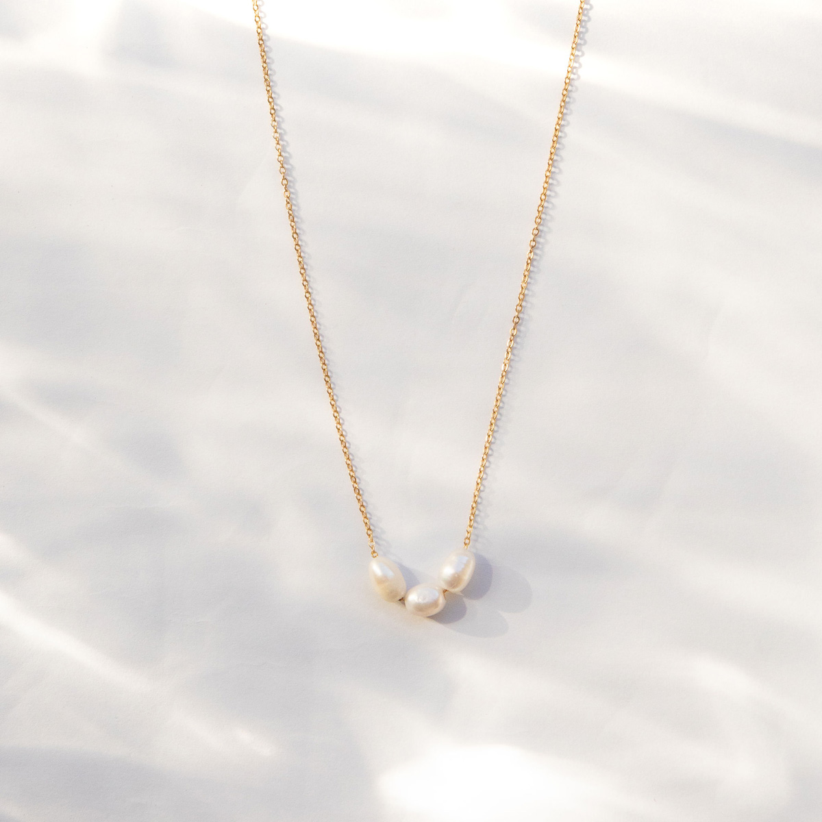 The Cloud Cluster Necklace, a trio of ringed oval pearls on a dainty gold tone cable.