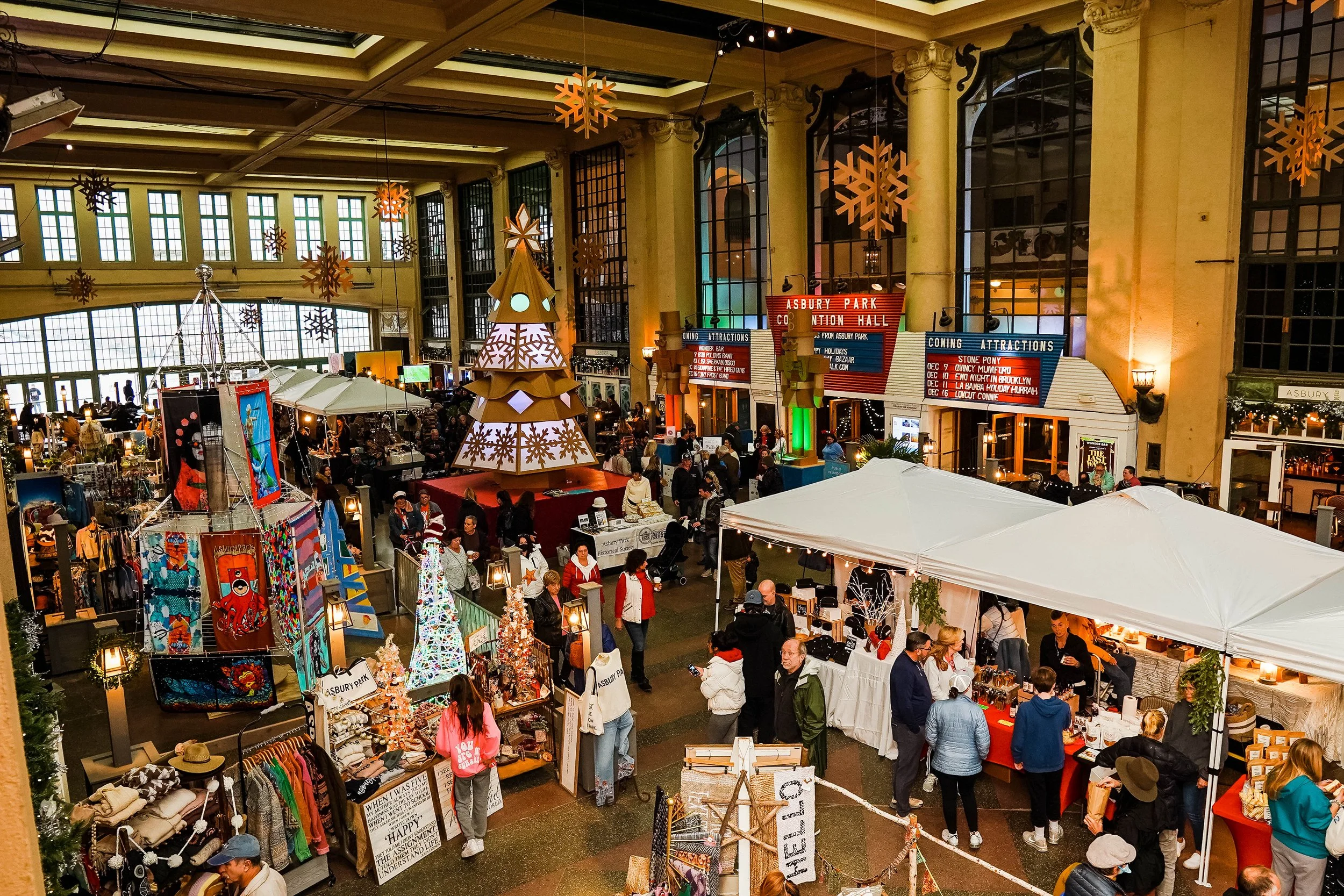 An art festival inside of the Grand Arcade on the Asbury Park boardwalk, filled with art vendors and shoppers.
